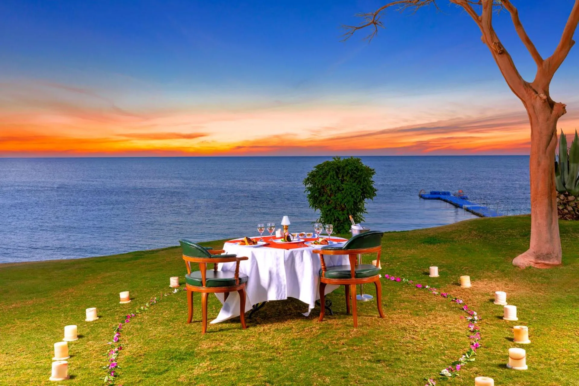 Table de dîner romantique en bord de mer au coucher du soleil.