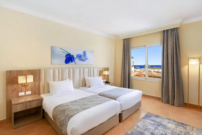 Une chambre lumineuse avec deux lits simples et une vue sur la mer.
