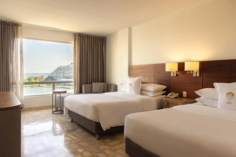 Chambre lumineuse avec deux lits simples et vue sur la mer.