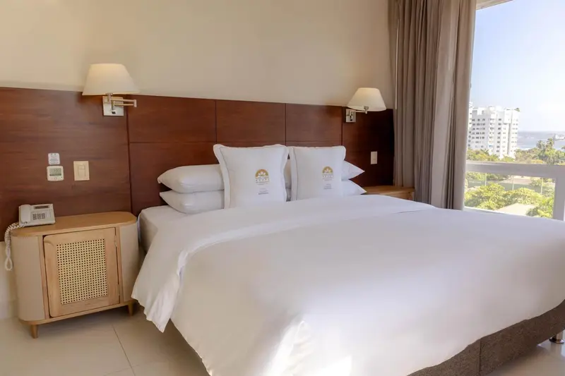 Une chambre d'hôtel lumineuse avec un grand lit recouvert de draps blancs.