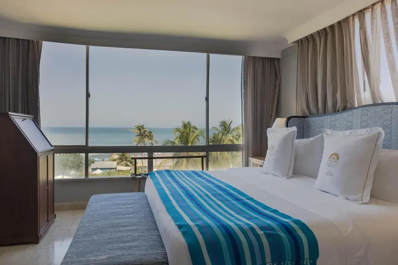 Chambre lumineuse avec un grand lit donnant sur une vue mer.