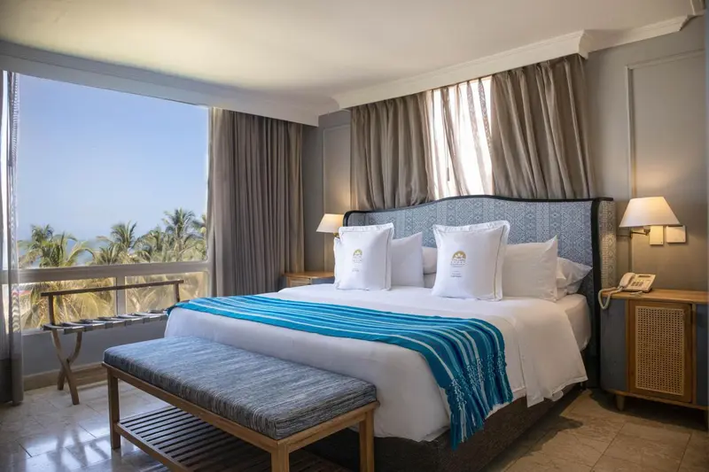 Une chambre lumineuse avec un grand lit et une vue sur la mer.
