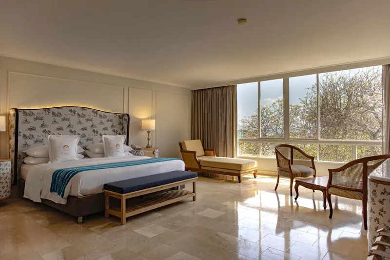 Une chambre lumineuse avec un grand lit et un coin salon près d'une fenêtre.