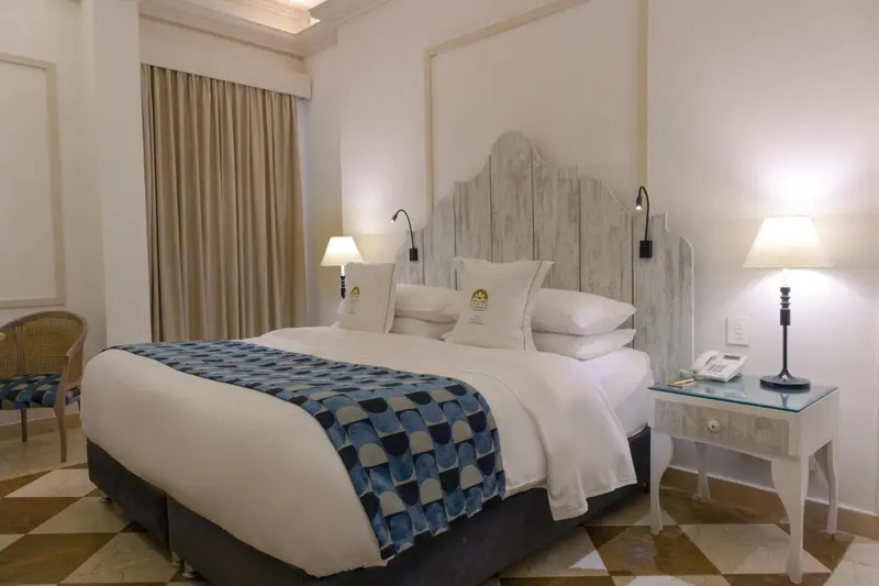 Une chambre lumineuse avec un grand lit recouvert d'une courtepointe bleue et blanche.