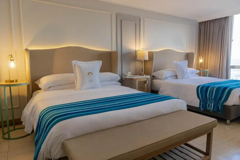 Une chambre lumineuse avec deux lits doubles et une décoration sobre.