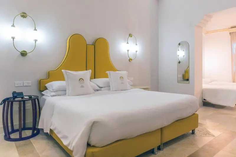 Une chambre lumineuse avec un grand lit recouvert de draps blancs et d'oreillers.