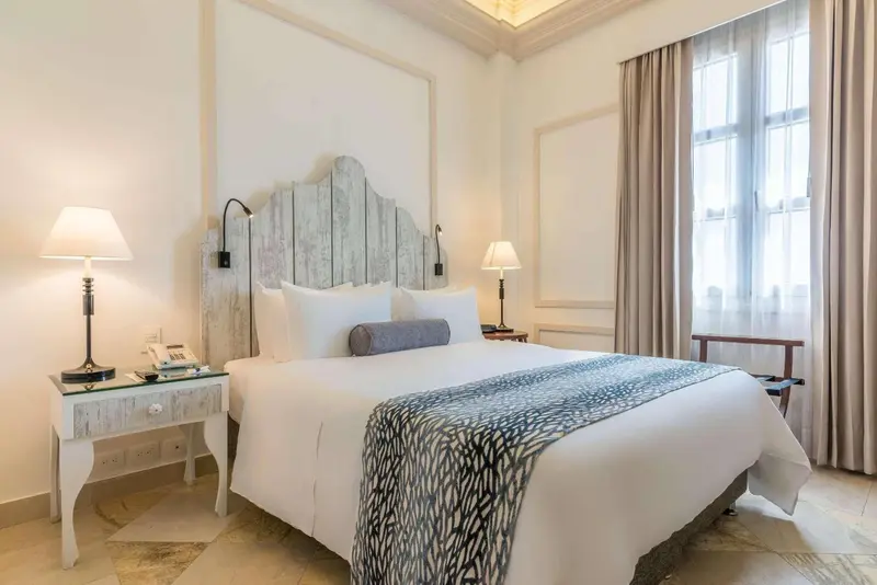 Une chambre lumineuse avec un grand lit recouvert d'une courtepointe décorative.