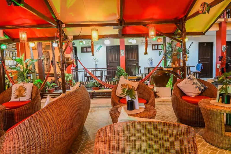 Espace de détente extérieur avec mobilier en rotin et végétation tropicale.
