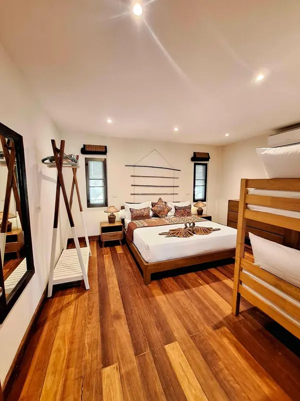 Chambre lumineuse avec un grand lit et un escalier en bois.