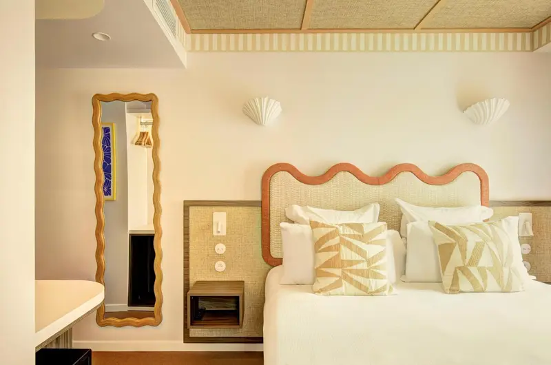 Une chambre lumineuse avec un grand lit décoré de coussins.
