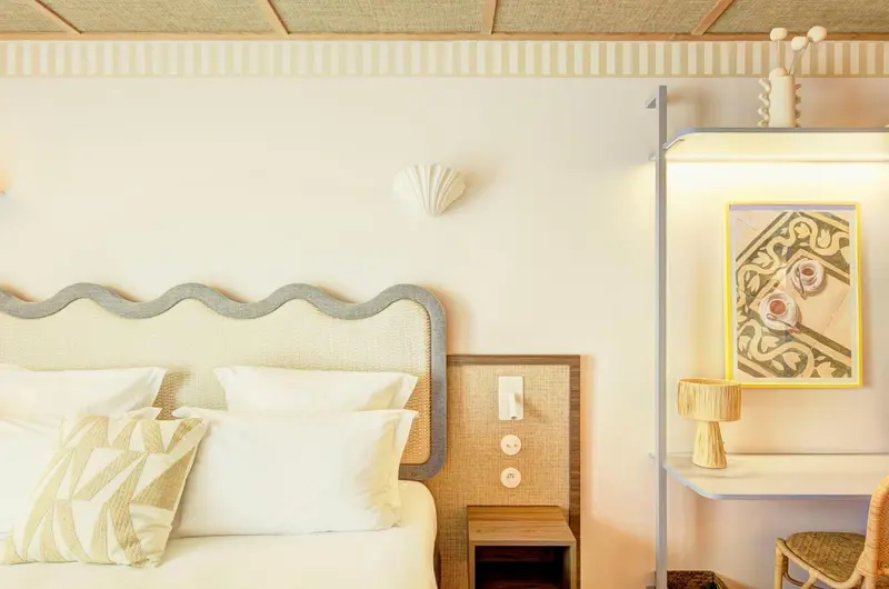 Une chambre lumineuse avec un lit décoré de coussins et une table de chevet.