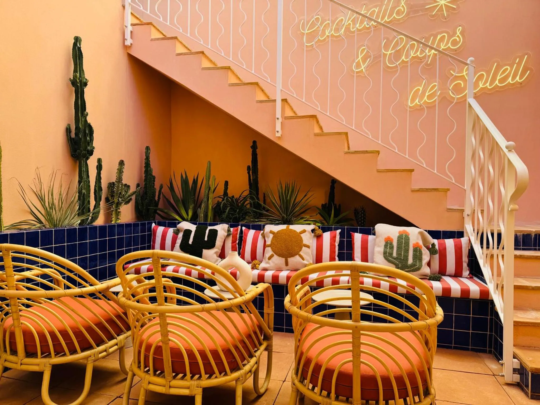 Espace de détente extérieur avec des fauteuils en rotin et des coussins colorés.