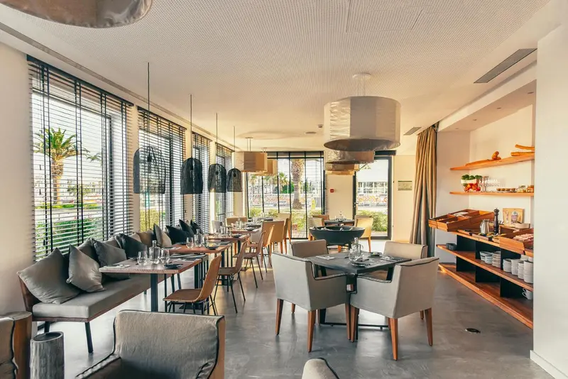 Une salle lumineuse avec des tables et des banquettes confortables près de grandes fenêtres.