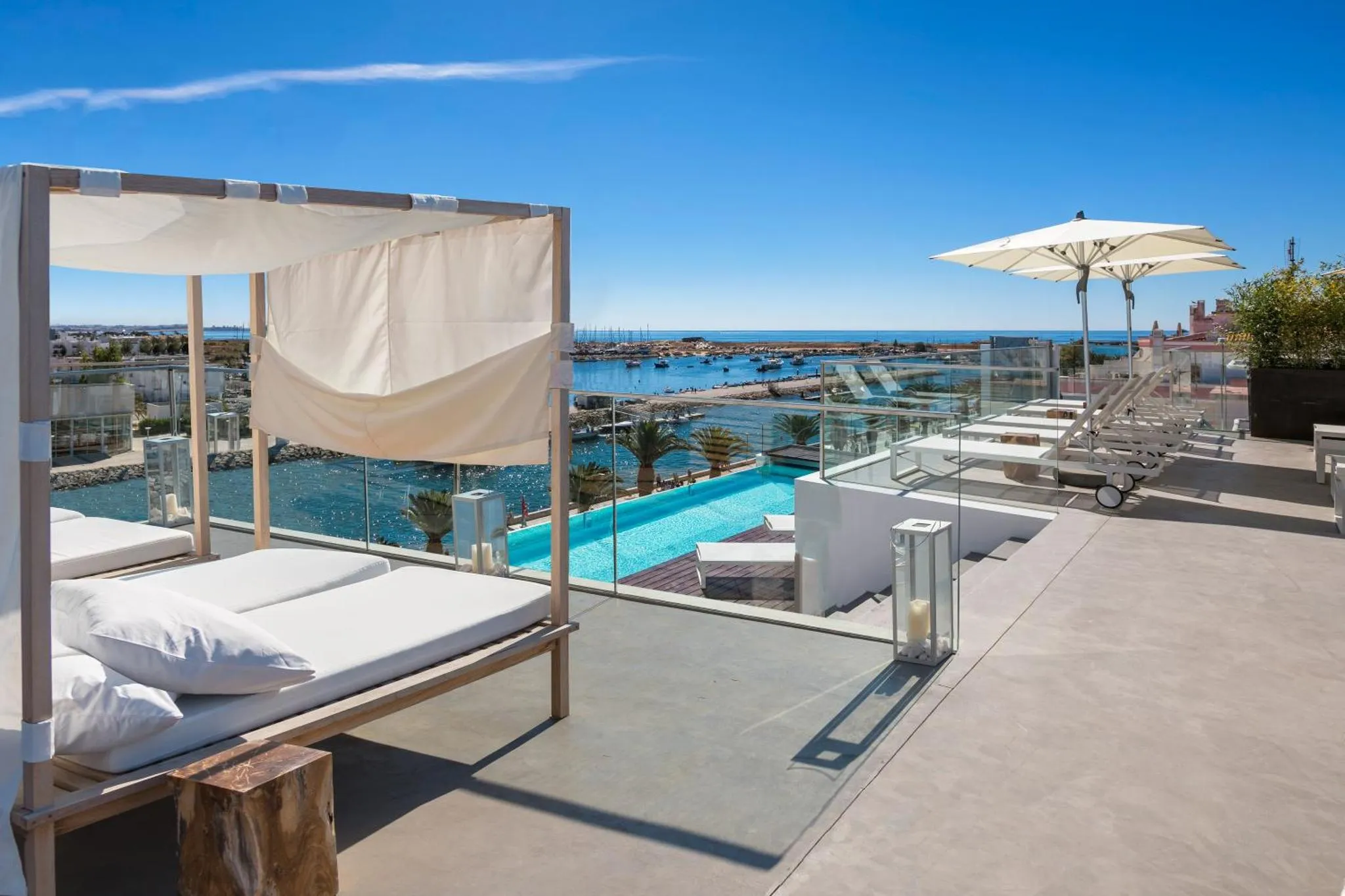 Terrasse aménagée avec des transats et une vue sur la mer et un port.