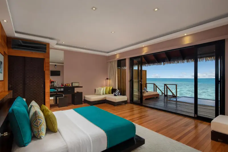 Une chambre lumineuse avec un grand lit et un accès direct à une terrasse sur pilotis.