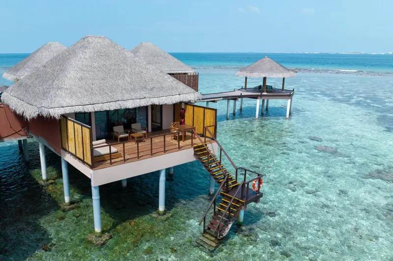 Maisons sur pilotis au-dessus d'une eau turquoise et claire.