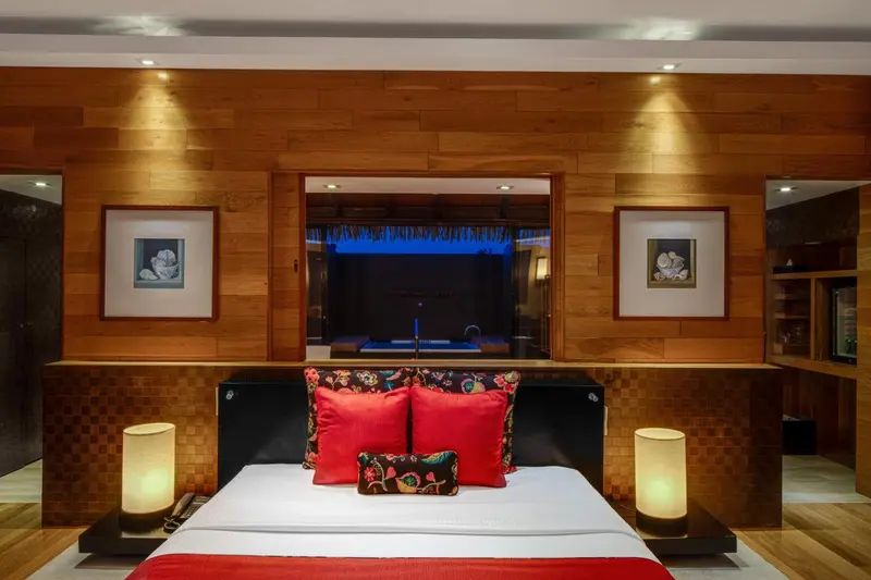 Une chambre à coucher avec un lit décoré de coussins et un accès à une piscine.