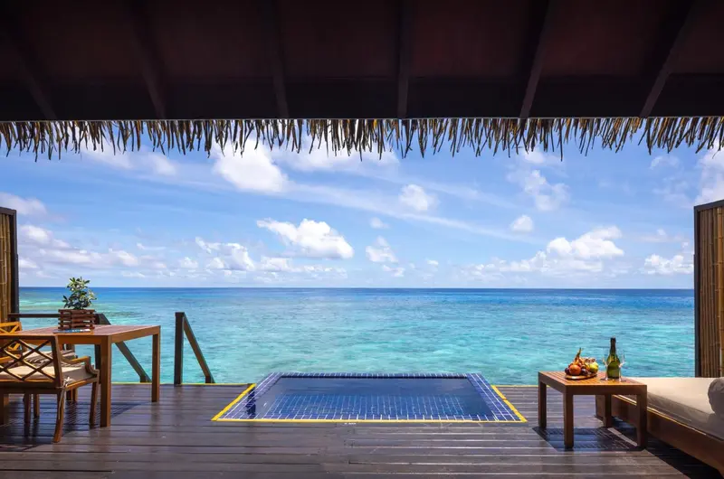 Vue sur l'océan turquoise depuis une terrasse avec jacuzzi.