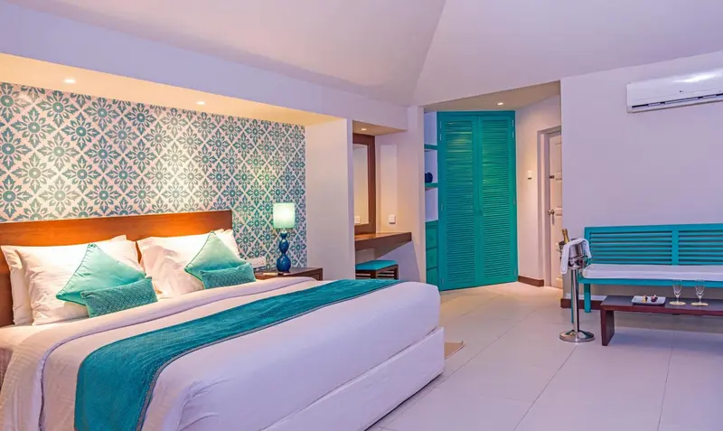 Une chambre lumineuse avec un grand lit et une décoration turquoise.