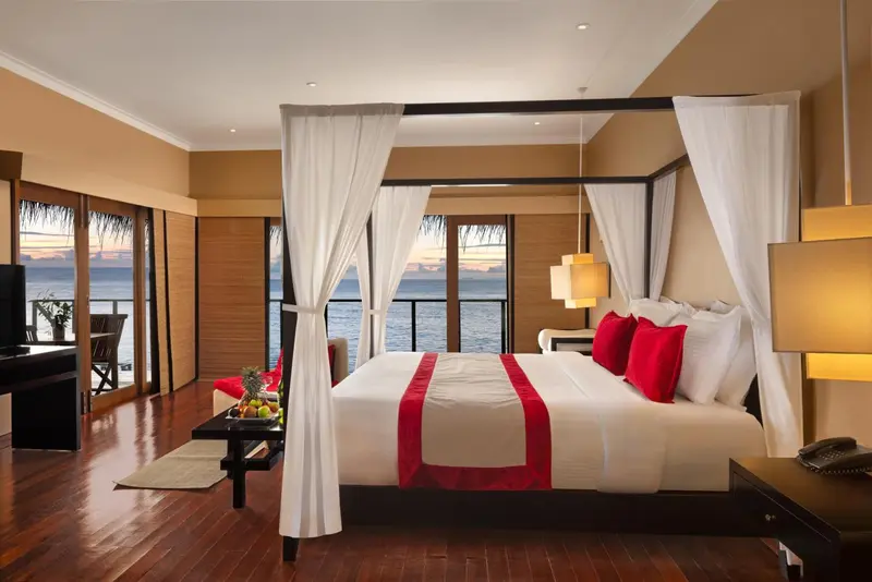 Une chambre avec un grand lit à baldaquin donnant sur l'océan.