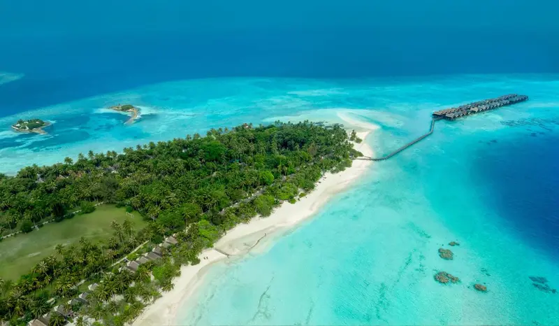 Vue aérienne d'une île tropicale bordée de plages et de végétation luxuriante.