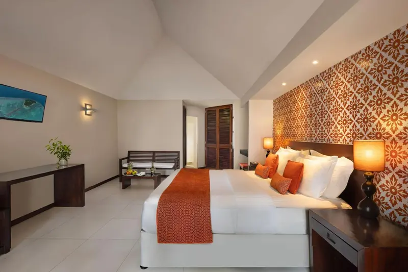 Chambre lumineuse avec un grand lit et une décoration murale colorée.