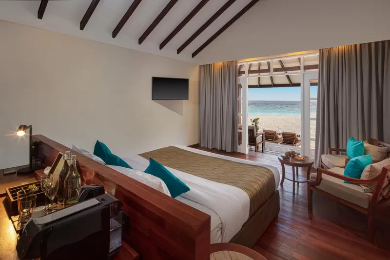 Une chambre avec un lit double donnant sur une plage.