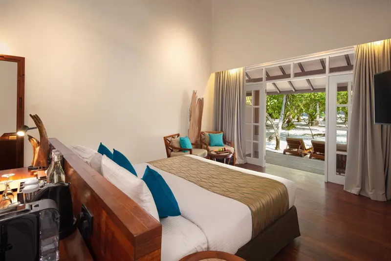 Une chambre lumineuse avec un grand lit et une vue sur une plage.