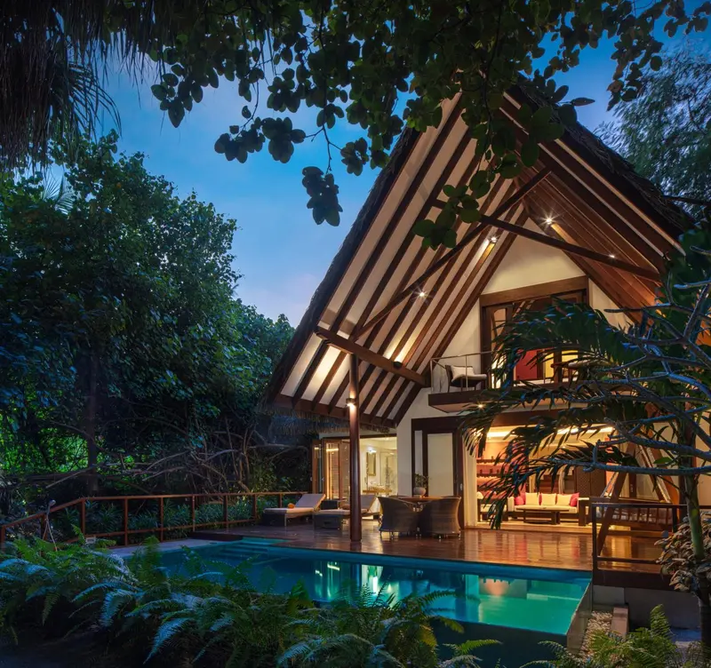 Une villa avec une terrasse lumineuse donnant sur une piscine et une végétation luxuriante.