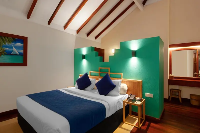 Chambre lumineuse avec un lit double et un mur turquoise.