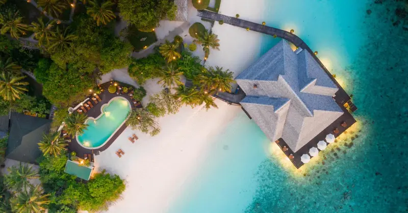 Vue aérienne d'un complexe hôtelier avec piscine et bâtiments au bord de l'eau.