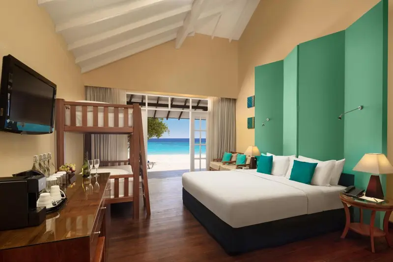 Une chambre lumineuse avec un lit double et un lit superposé donne sur la mer.