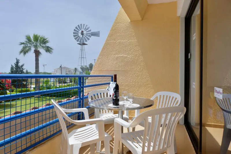 Terrasse avec mobilier blanc donnant sur un jardin et une vue lointaine.