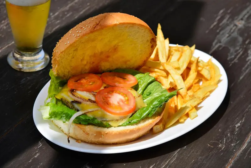 Un hamburger garni et des frites sont servis sur une assiette blanche.