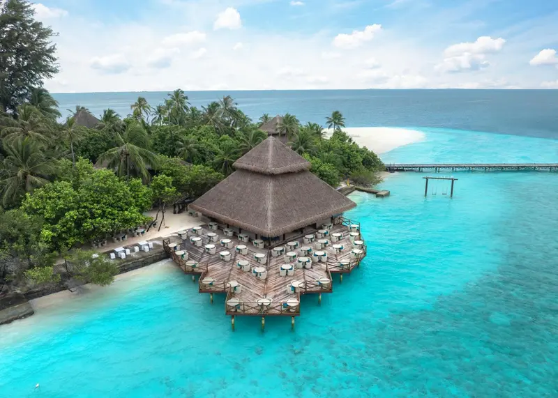 Vue aérienne d'un restaurant sur pilotis au-dessus d'une eau turquoise.