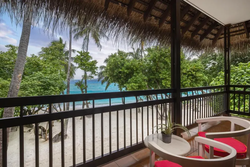 Terrasse avec mobilier blanc donnant sur une plage de sable fin et la mer.
