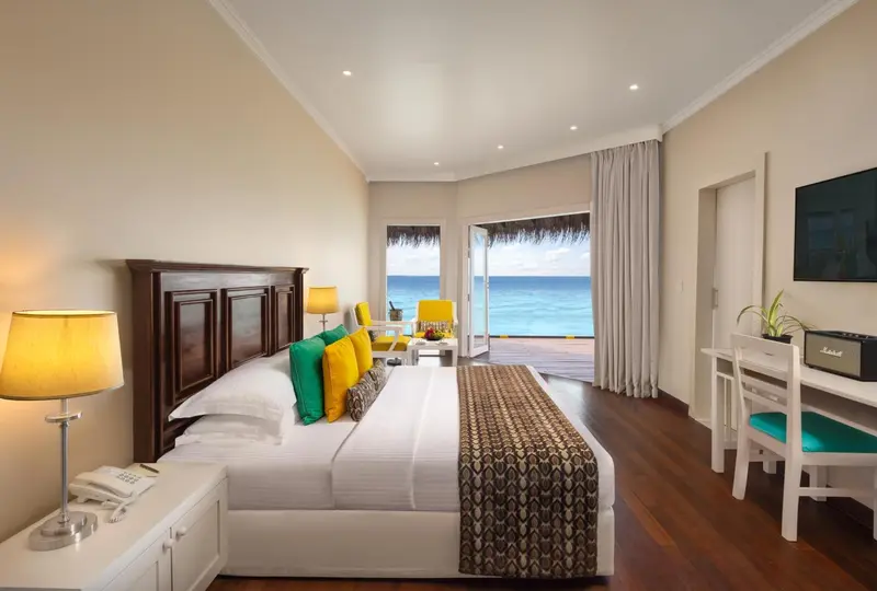 Chambre lumineuse avec un grand lit et vue sur l'océan.