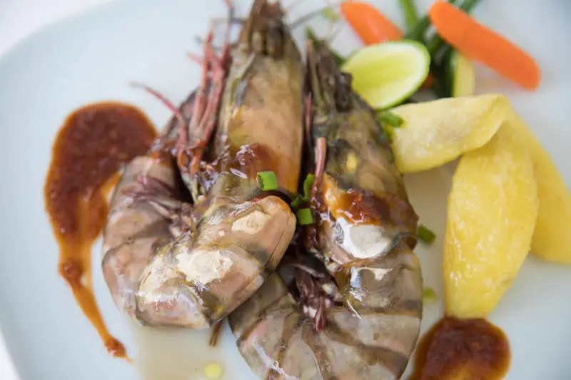 Assiette de crevettes grillées accompagnées de légumes et de pommes de terre.