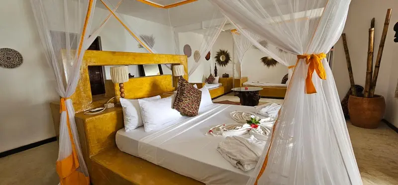 Une chambre lumineuse avec un lit à baldaquin décoré de moustiquaire et de fleurs.