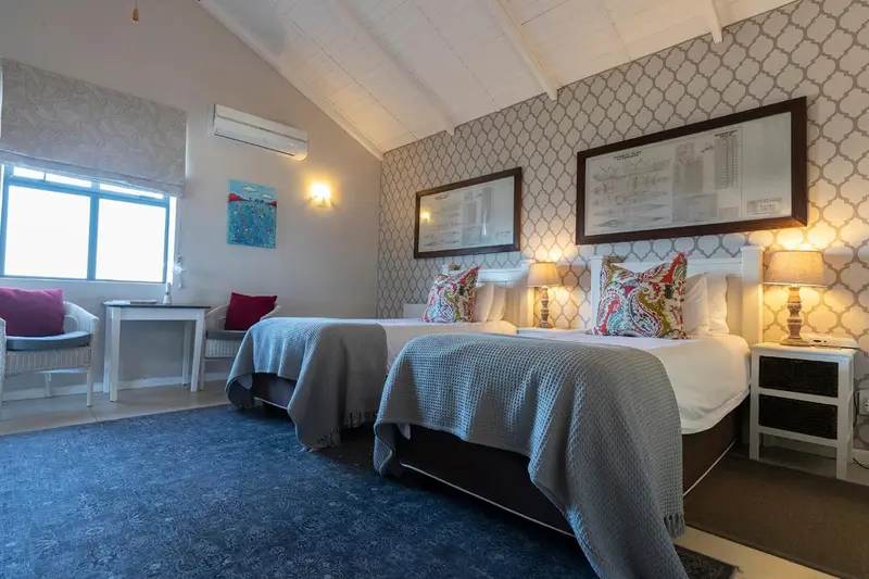 Chambre lumineuse avec deux lits simples et décoration florale.
