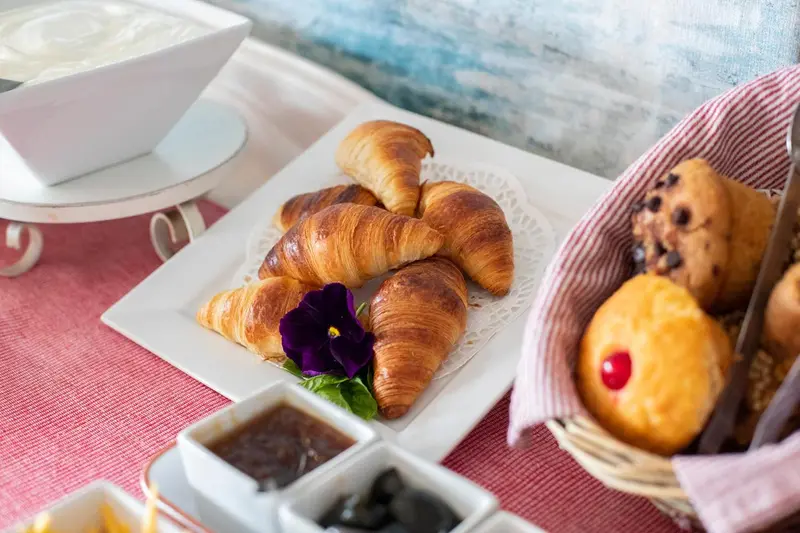 Assortiment de viennoiseries et confitures présentées sur une table.