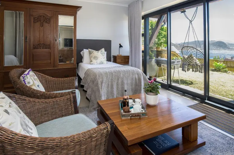 Une chambre lumineuse avec un lit simple et un coin salon donnant sur une vue dégagée.