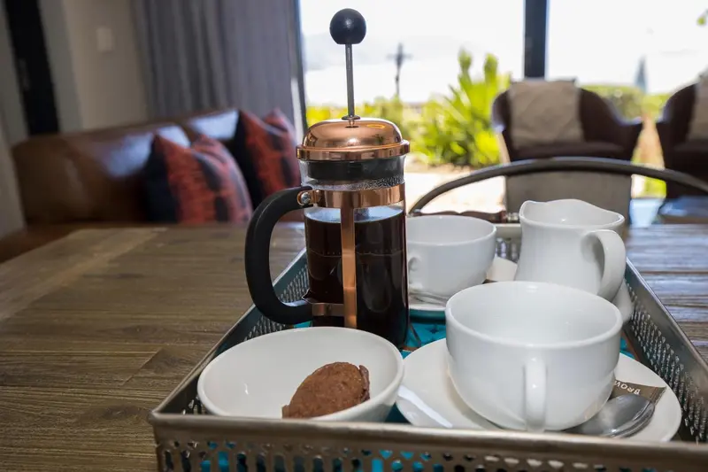 Une cafetière et une tasse de café sont posées sur une table.