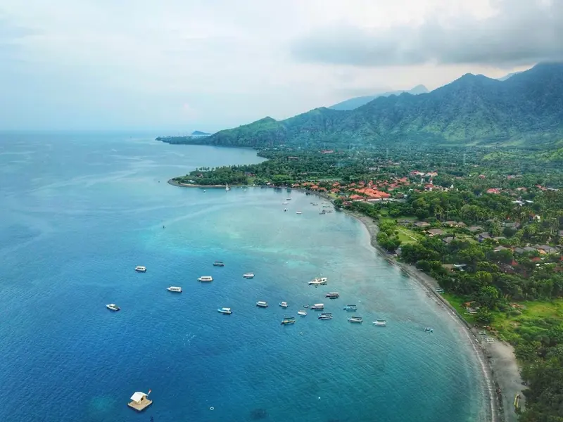 Vue aérienne d'une côte rocheuse bordée d'une plage et de bateaux.