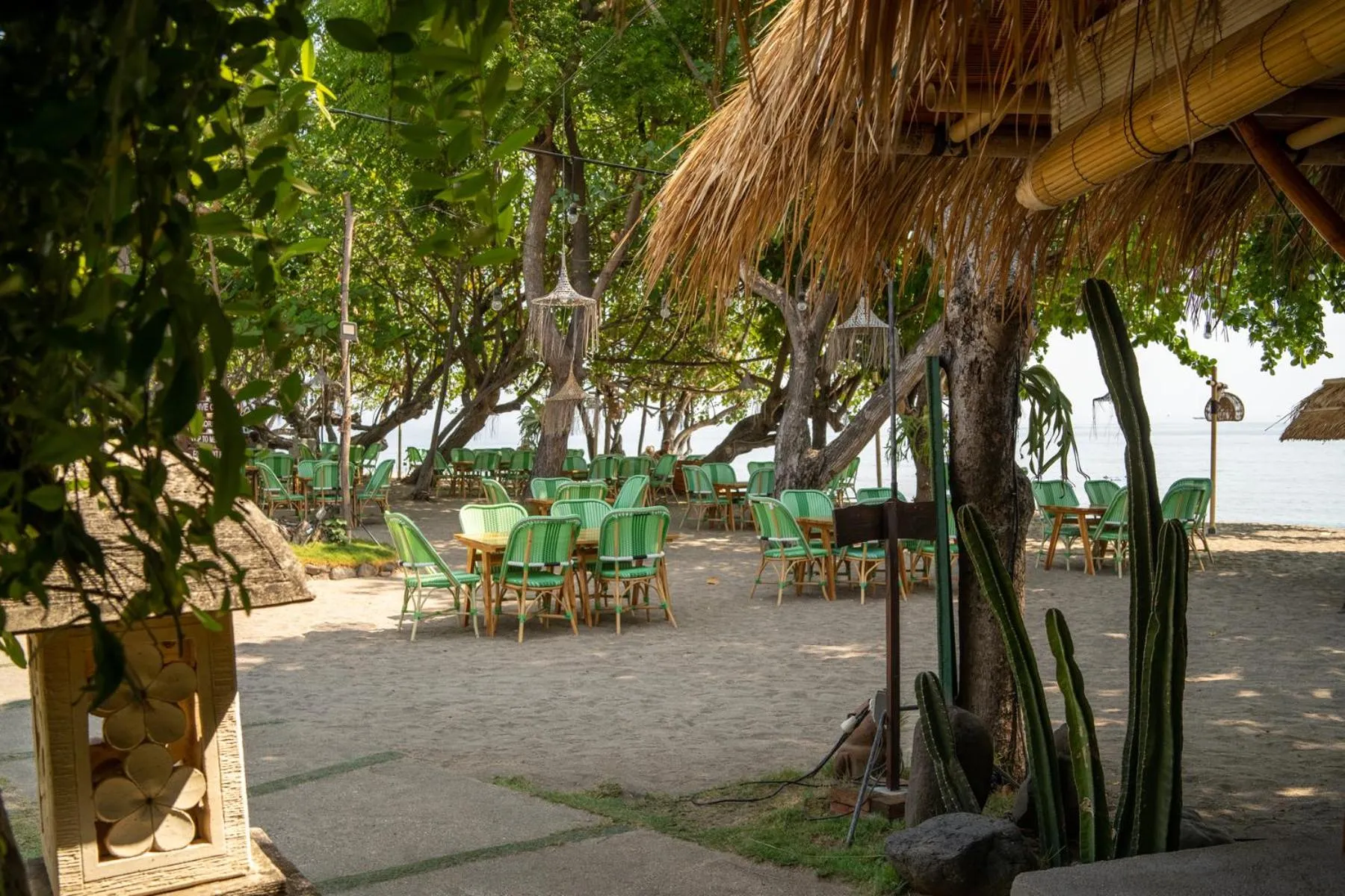 Terrasse ombragée avec tables et chaises en bord de mer.