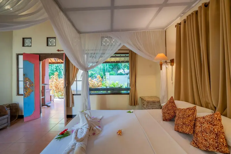 Une chambre lumineuse avec un lit à baldaquin donnant sur une végétation luxuriante.
