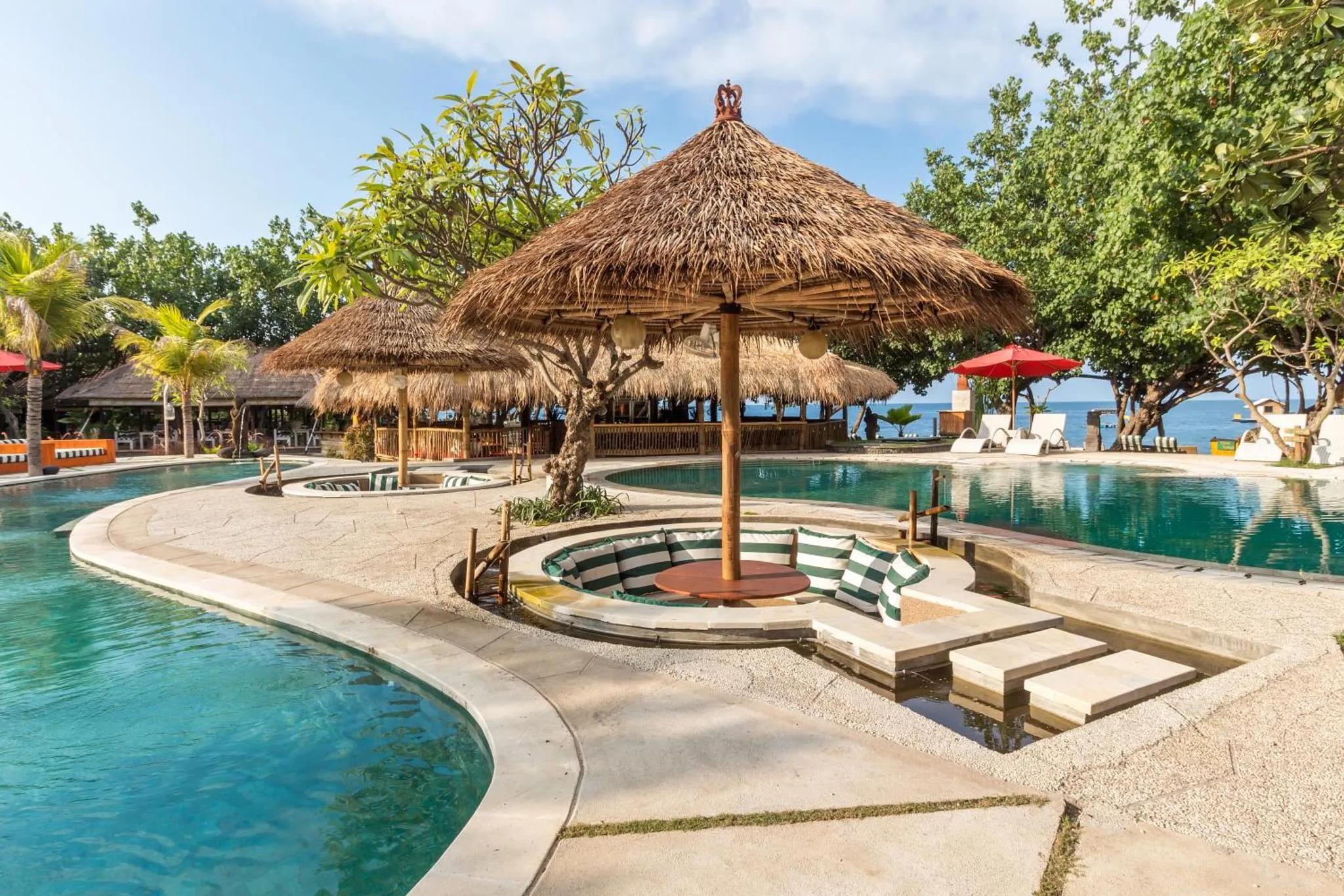 Piscine sinueuse avec des espaces de détente ombragés et des chaises longues.