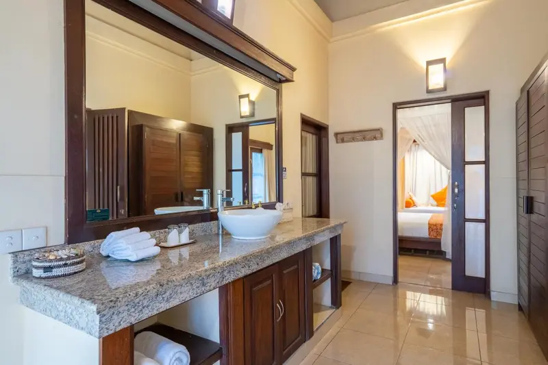 Une salle de bain lumineuse avec un grand miroir et un plan vasque en marbre.