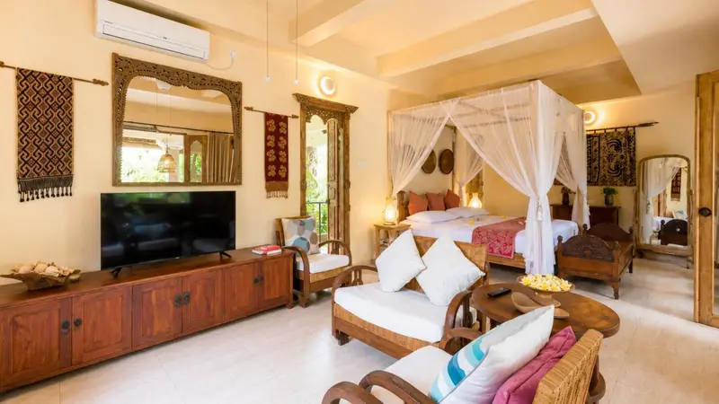 Une chambre lumineuse avec un grand lit à baldaquin et un coin salon.