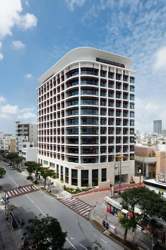 Bâtiment moderne à plusieurs étages avec des balcons et une façade blanche et brune.